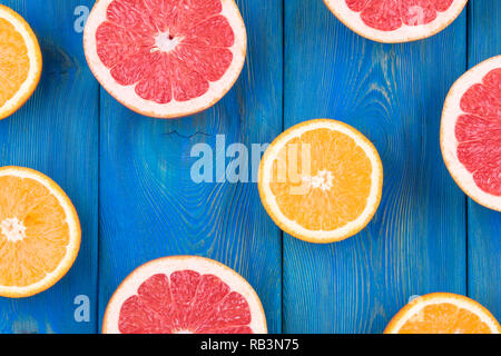 Fresh half cut grapefruit and orange on a blue wooden background, close up view Stock Photo