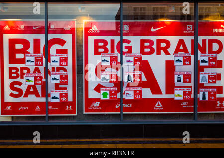 Shop window for a national chain store filled with posters offering Sale of Big Brands at reduced prices on the 18th December showing difficulty in th Stock Photo