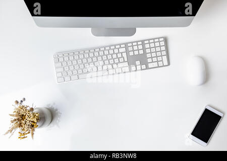 Top view of office working place with desktop computer. Flat lay of PC, cell phone and numeric keyboard on clean white table Stock Photo