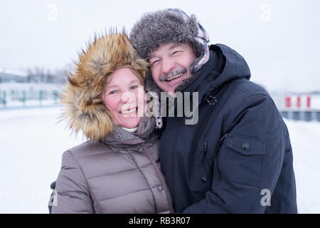 Portrait of elderly couple having fun outdoors in winter smiling and looking at camera Stock Photo