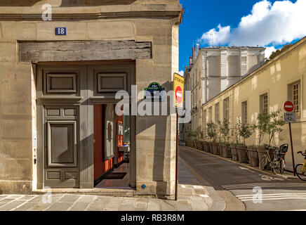 Open wooden doorway next to an narrow street on Rue Saint-Louis en l'Île on a summers morning in Paris Stock Photo