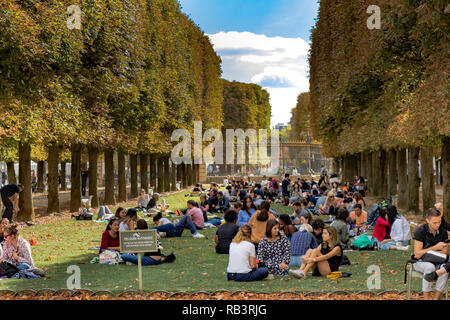 People sitting on the lawn at Jardin Du Luxembourg Gardens enjoying the summer sunshine ,Paris Stock Photo