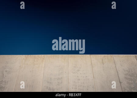 A wall of prefabricated concrete against a dark blue sky with open negative space Stock Photo