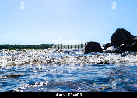 Big windy waves splashing over rocks. Wave splash in the lake against beach. Waves breaking on a stony beach, forming a spray. Water splashes. Water s Stock Photo