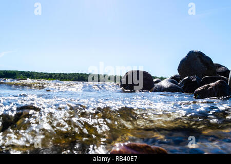 Big windy waves splashing over rocks. Wave splash in the lake against beach. Waves breaking on a stony beach, forming a spray. Water splashes. Water s Stock Photo