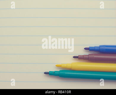four colored markers on a white Notepad background, close-up, copy space. place for text. school topics. study concept. Stock Photo