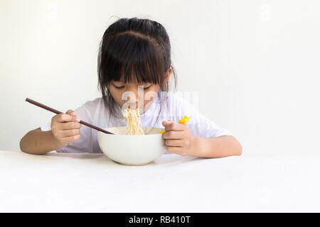 Portrait of Asian child girl eating instant noodles with white wooden table and white background. Stock Photo