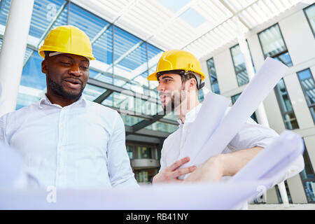 Two architects with architectural drawings work together as a team Stock Photo