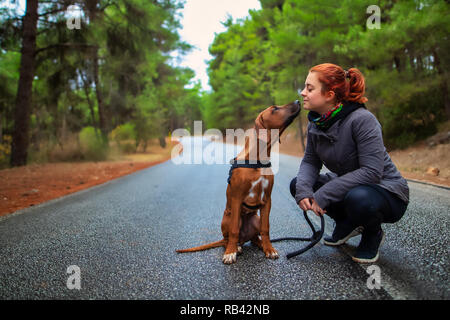 Portrait of happy teenage girl and Rhodesian ridgeback dog . Dog giving girl sweet kiss lick. Love animals love my pet Stock Photo