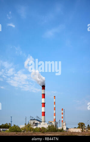 Power plant smoky chimney against the blue sky. Stock Photo