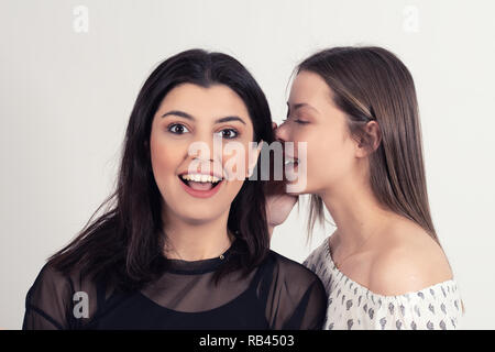 Young woman telling her girlfriend some secret. Two women gossiping. Stock Photo