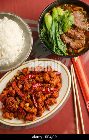 Chong Qing style chicken with a side of rice and Taiwanese braised beef noodle soup on the table of a Chinese restaurant Stock Photo