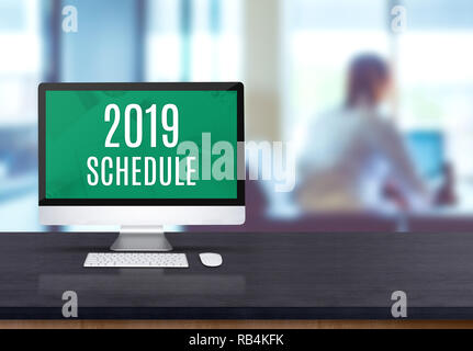 2019 schedule on desktop computer on black board wooden table top with blur people working at office desk bokeh background Stock Photo