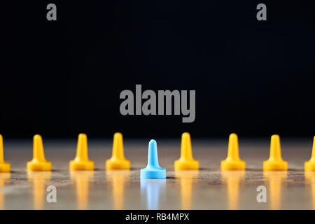 Individuality and leadership concept. Blue figure standing out from a yellow figures Stock Photo