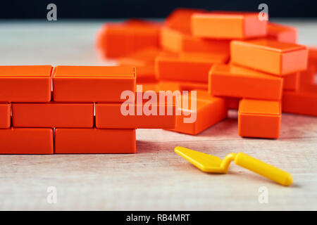 Brickwork from toy blocks and trowel. Unfinished construction concept Stock Photo