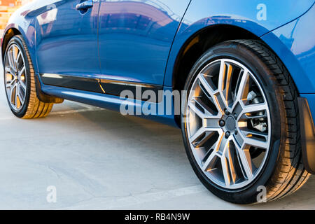 Tire and alloy wheel of a modern blue car on the ground, car exterior details Stock Photo