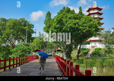 A man passes the bridge leading to Chinese and Japanese Gardens, in Jurong East, Singapore, in the background a 7-storey Chinese pagoda Stock Photo