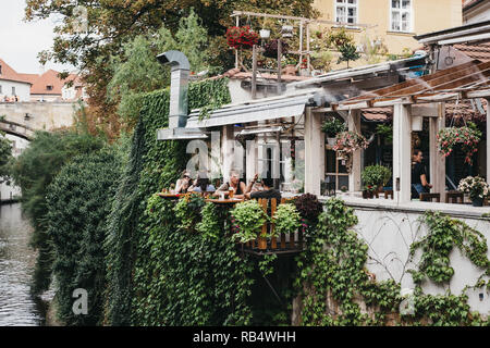 Prague, Czech Republic - August 23, 2018: People drinking beer at the outdoor tables of Velkopřevorský Mlýn restaurant in Mala Strana, Prague. Beer is Stock Photo