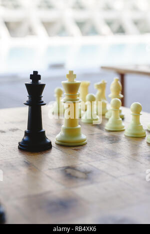 Black and white chess kings faced between defocused pieces on wooden board. Stock Photo