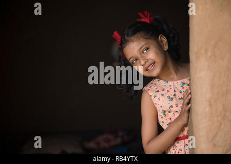 Little Indian girl peeking out of her house in village Stock Photo