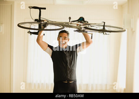 Mature man lifting his bike in the air Stock Photo