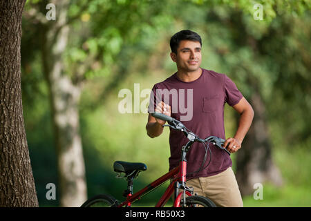 Cyclist standing with his bicycle in the park. Stock Photo