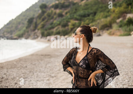 Young female wearing black lace tunic enjoying beatiful bay. Stock Photo