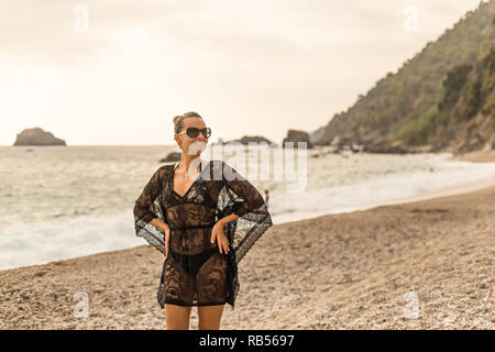 Young female wearing black lace tunic enjoying beatiful bay. Stock Photo
