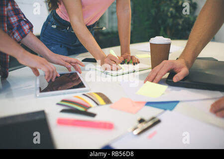 Picture of people working together at one table. They hold stickers and markers. Hands pointing. Stock Photo