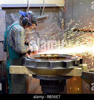 workers in safety clothing sanding a casting in an industrial company Stock Photo