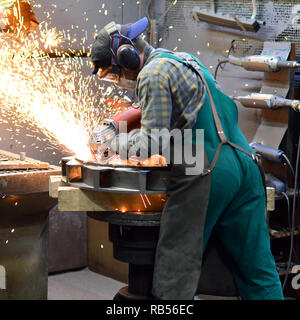 workers in safety clothing sanding a casting in an industrial company Stock Photo