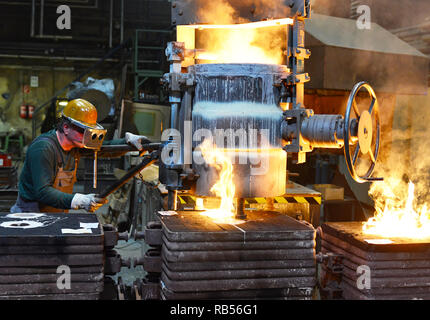 workers in a foundry casting a metal workpiece - safety at work and teamwork Stock Photo