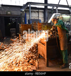 workers in safety clothing sanding a casting in an industrial company Stock Photo