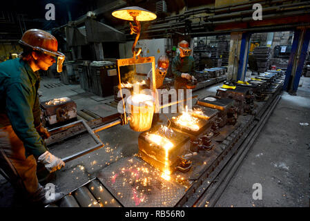 workers in a foundry casting a metal workpiece - safety at work and teamwork Stock Photo