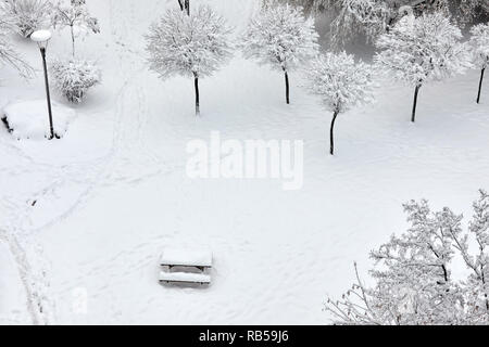 Wooden bench picnic table in a park covered with snow in winter Stock Photo