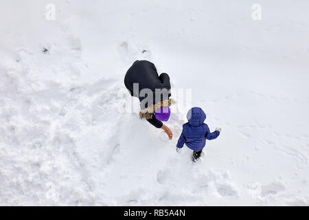 Above aerial view of a mother and her little boy play in the snow in winter time Stock Photo