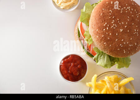 Burger with chips and sauces on white table. Top view. Horizontal composition. Stock Photo