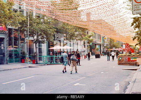 Montreal, Canada - June, 2018: People walking on the street of gay village under the symbolic colorful balls in Montreal, Quebec, Canada. Editorial. Stock Photo