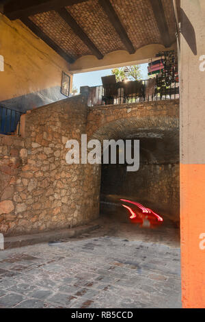 Red car entering Guanajuato underground tunnel, with walkway above Stock Photo