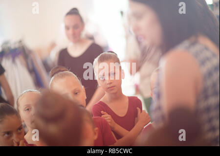 group of young russian caucasian ballerina girls hearing teacher advice during indoors rehearsal Stock Photo
