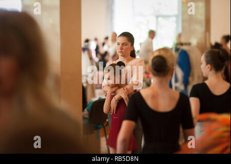 young beautiful mother embracing her little ballerina dancer girl standing in dance school during rehearsal before show Stock Photo