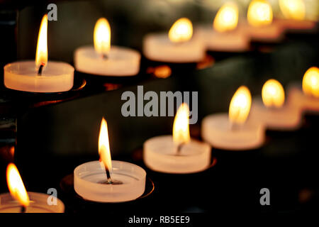 Lit tealight Candles in a church with bokeh Stock Photo