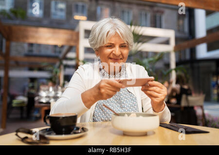 senior woman photographing food at street cafe Stock Photo