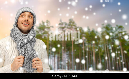 smiling man in hat and scarf over winter forest Stock Photo
