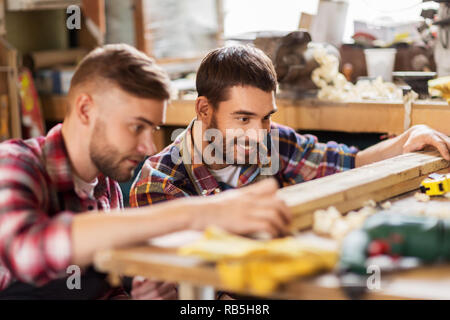 carpenters measuring wooden board at workshop Stock Photo