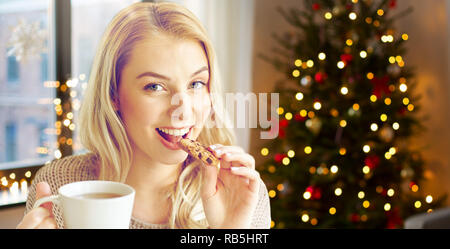 woman with tea eating cookie on christmas at home Stock Photo