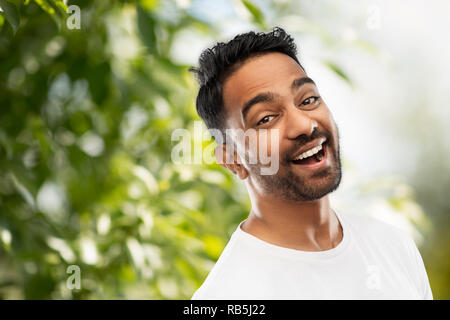 laughing indian man over green natural background Stock Photo