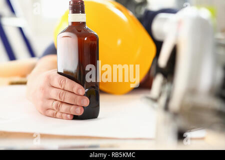 Arm of drunken worker in yellow helmet Stock Photo