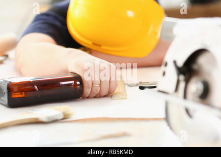 Arm of drunken worker in yellow helmet Stock Photo