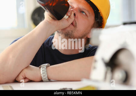 Arm of drunken worker in yellow helmet Stock Photo